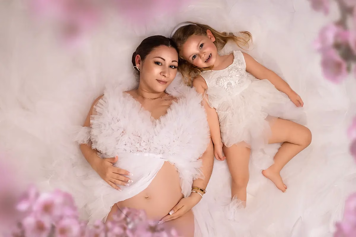 image représentant une femme enceinte avec sa fille allongée dans un décor floral