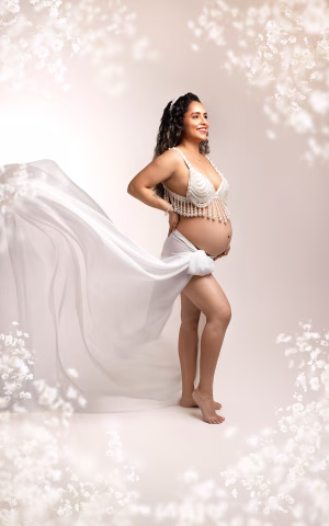 L'image représente une femme enceinte lors d'une séance grossesse dans un voile le blanc dans un style épuré et floral