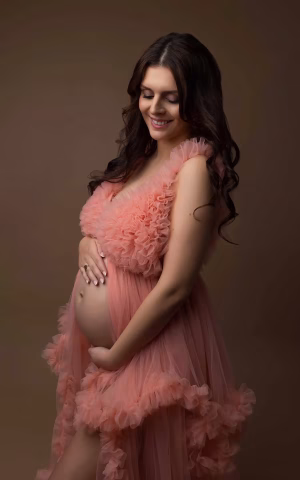femme enceinte dans une robe rose en studio